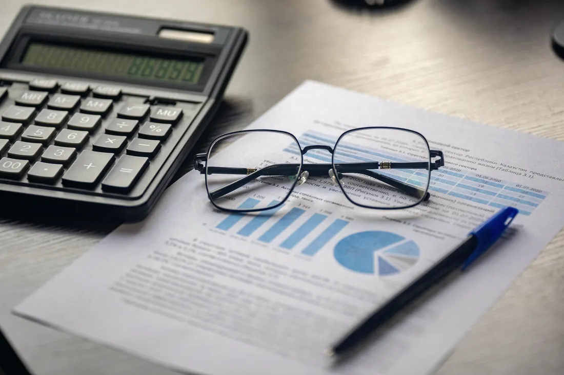 Financial report with charts, a calculator, and reading glasses on a CPA's desk